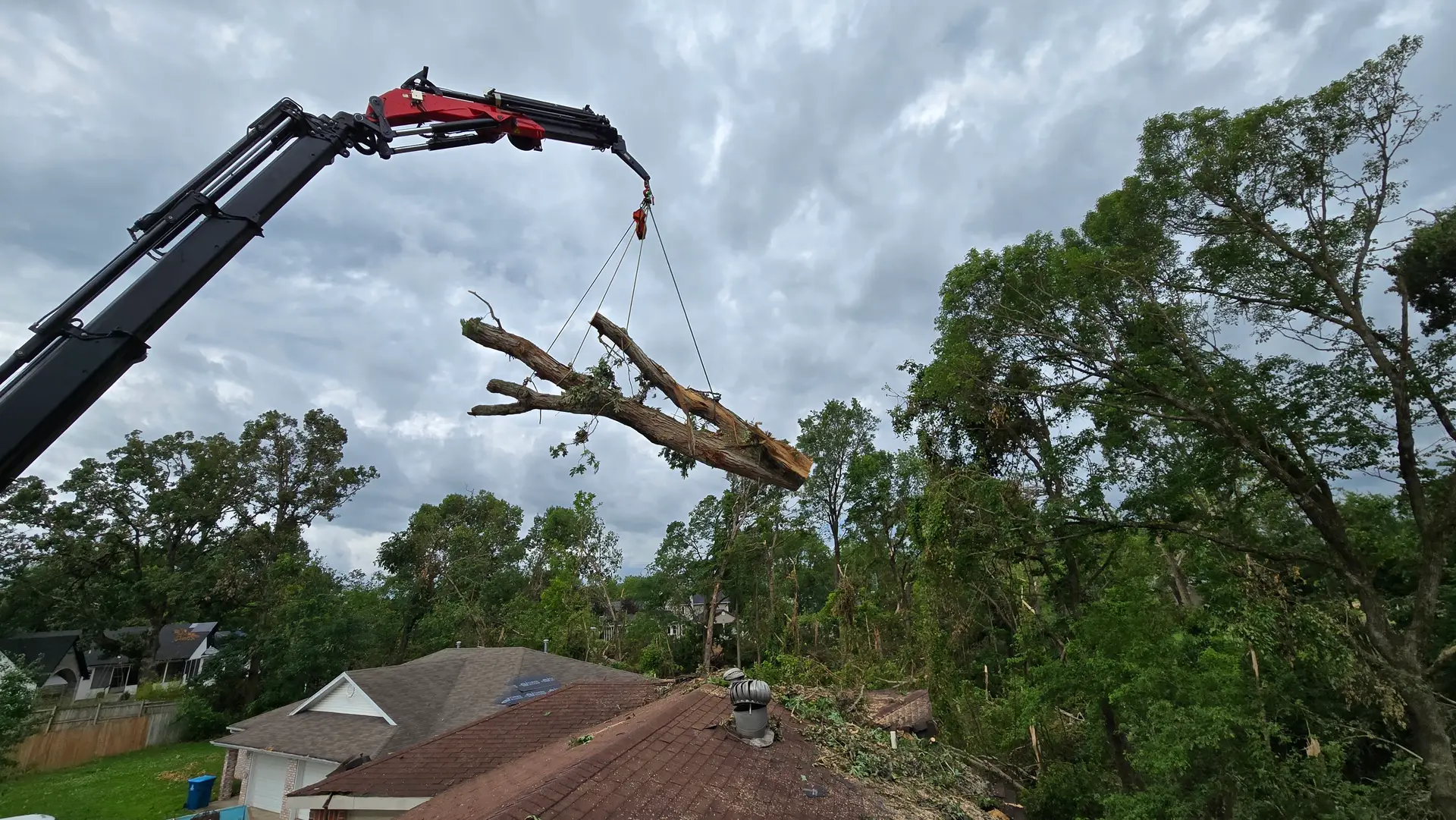 Crane removing a storm-damaged tree from over a house in Arkansas